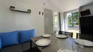 A dining area with a table set for four, a sofa with blue cushions, and a kitchen area visible through an open door.