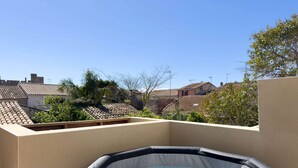 Una azotea con jacuzzi, techos de tejas de terracota y un cielo azul despejado.