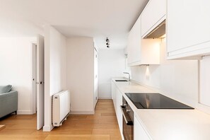 Una cocina moderna con armarios blancos, encimera negra y horno integrado.