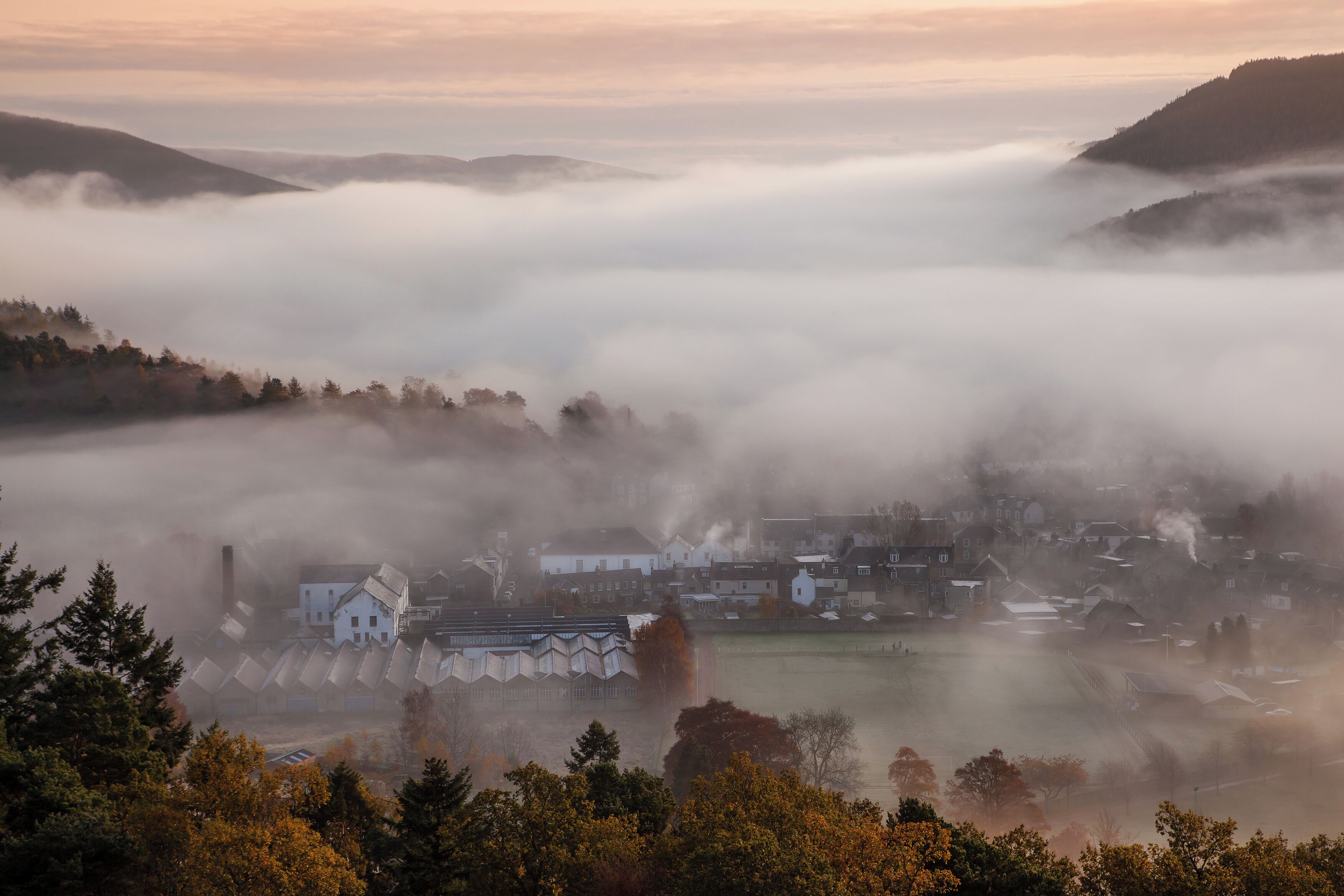 A town nestled in a valley with buildings surrounded by fog.
