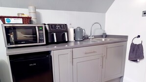 Una cocina moderna equipada con microondas, cafetera, hervidor y lavavajillas.