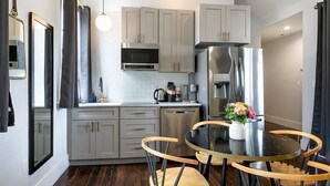 Una cocina moderna con gabinetes grises, electrodomésticos de acero inoxidable, una mesa redonda con sillas de madera y un florero con flores.