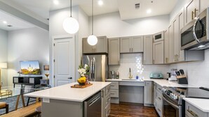 Uma cozinha moderna com ilha central, eletrodomésticos de aço inoxidável e armários em tons claros.