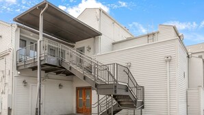 Um edifício de dois andares com uma escadaria central, uma porta de garagem e uma pequena varanda.