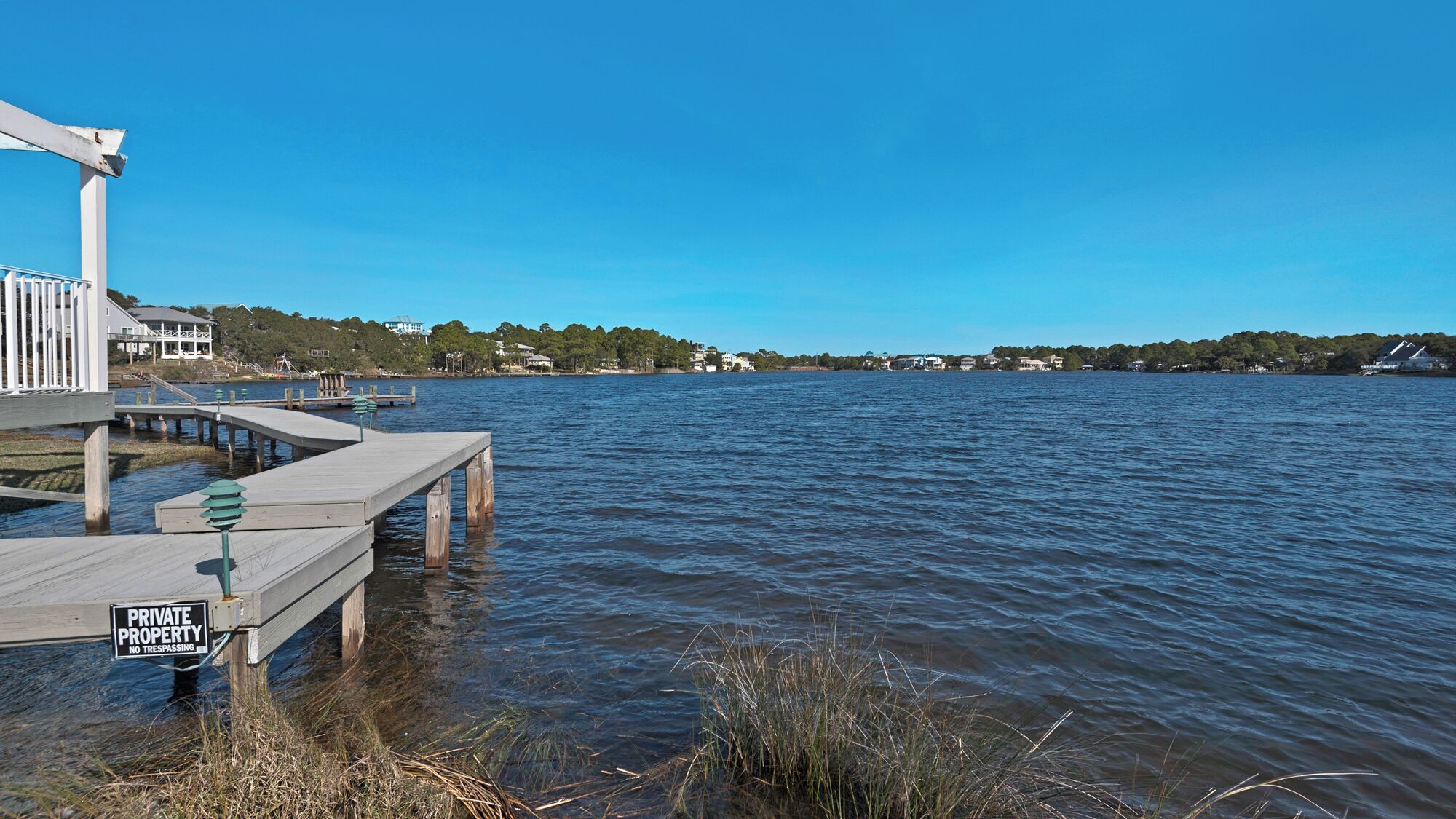 A wooden pier extending into calm water, with a 'PRIVATE PROPERTY NO TRESPASSING' sign visible.
