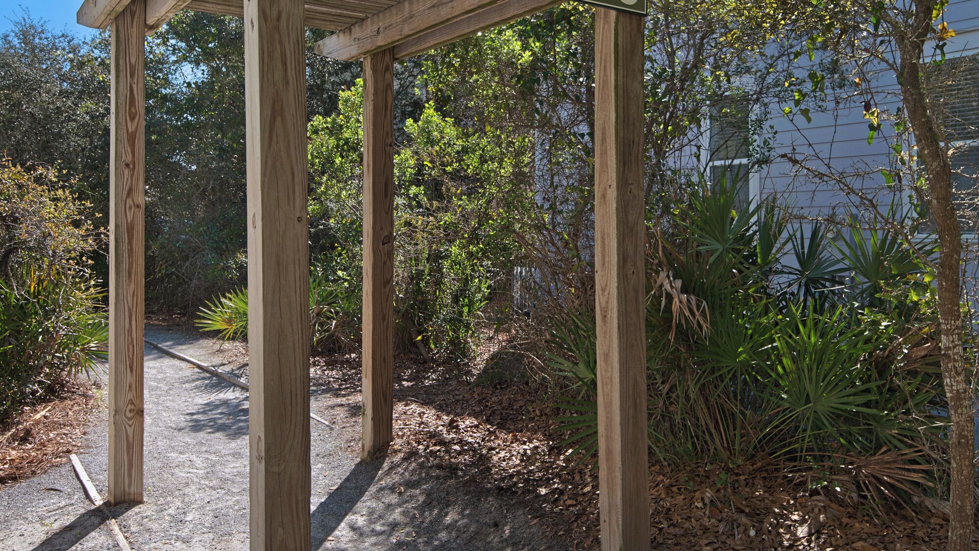 Eine hölzerne Pergola in einem Garten mit verschiedenen Pflanzen und einem Weg.