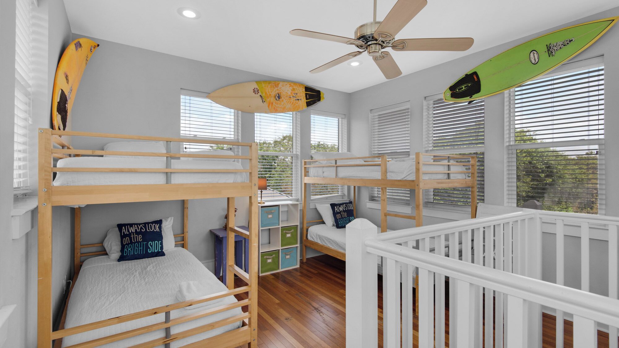 A bunk bed room with a ceiling fan, a surfboard, and a window with blinds.