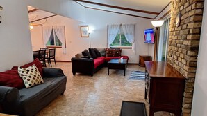 Ett vardagsrum med en soffa, ett soffbord, en tv och en tegelvägg.