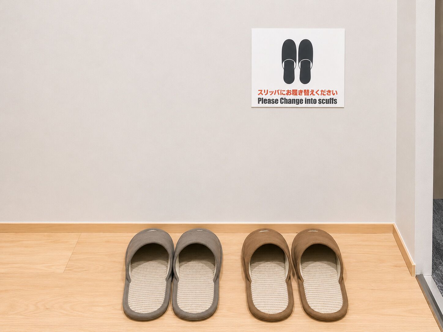 Et par slippers på gulvet, og et skilt over dem med tekst og en illustration af slippers.