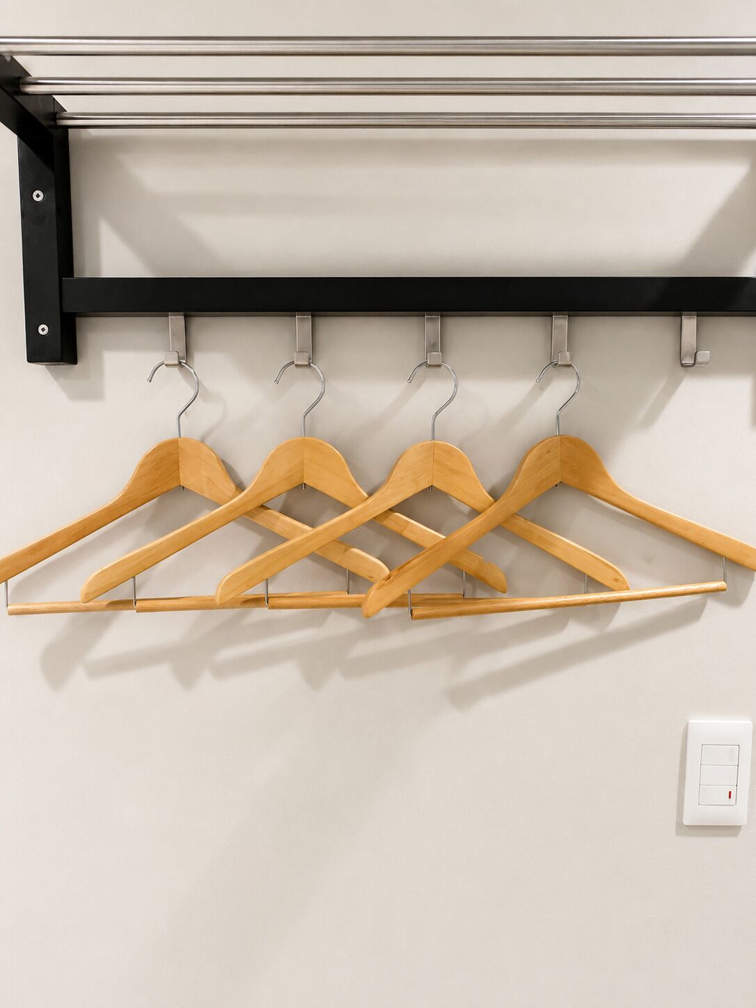 Un perchero de pared con cuatro perchas de madera.