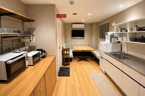 A compact kitchen with a microwave, coffee maker, and a small dining table. - My Home Inn Sennan Onosato (Sennan)