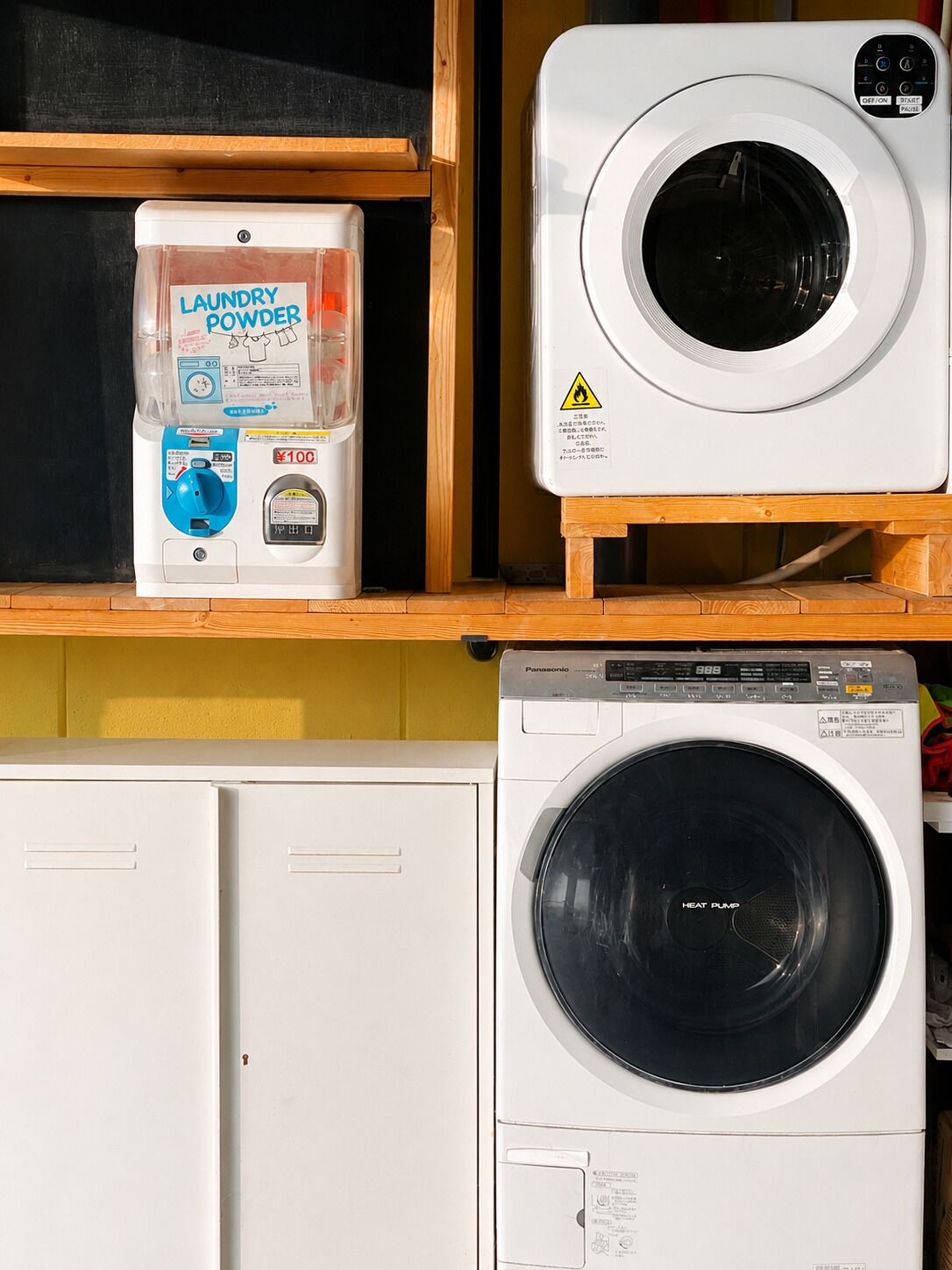 A laundry area with a washing machine, a dryer, and a container of laundry powder.