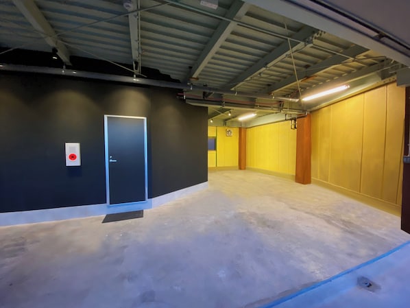A spacious indoor area with a door, yellow walls, and a concrete floor. - My Home Inn Sennan Onosato (Sennan)