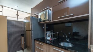 Una cocina moderna con microondas integrado, pileta de acero inoxidable y muebles de madera.