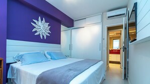 Un dormitorio moderno con cama, un gran elemento decorativo en la pared y un baño visible a través de una puerta abierta.