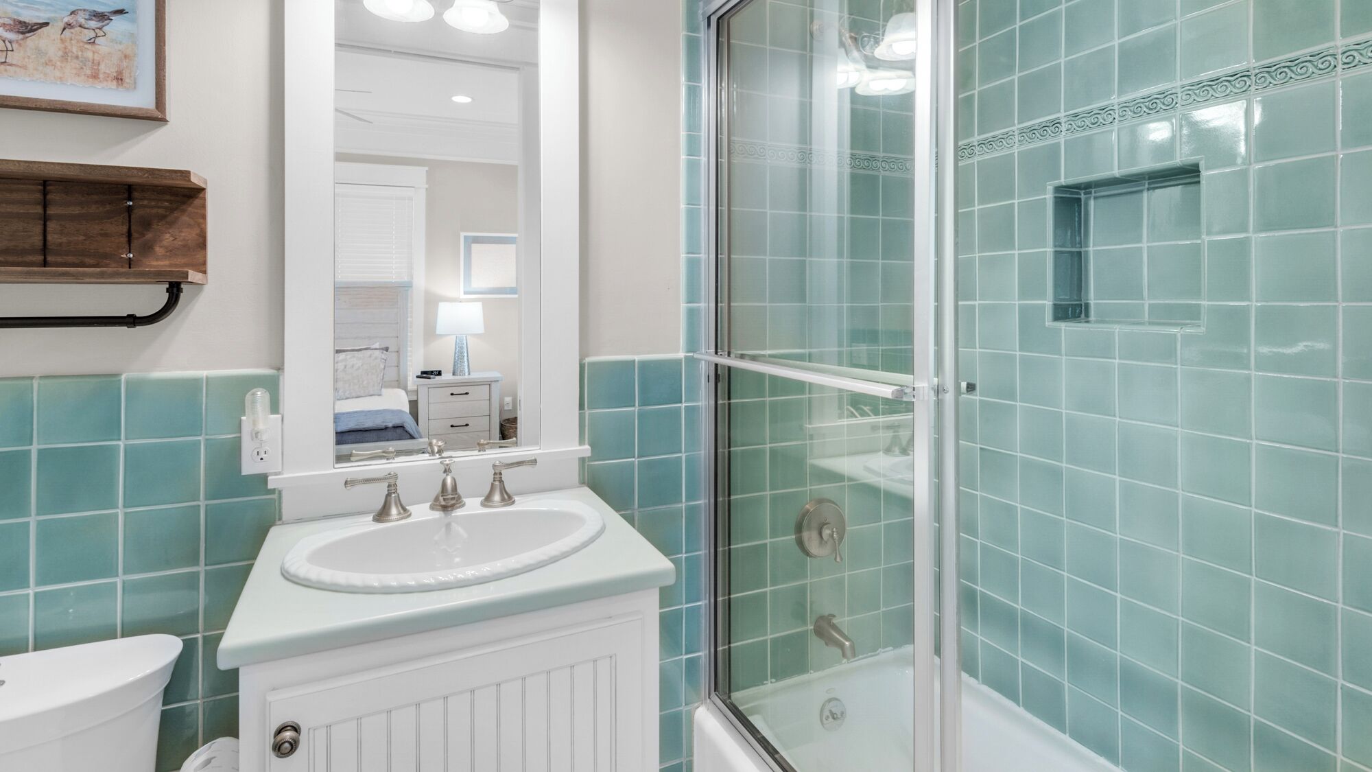 Une salle de bain avec un lavabo blanc, une douche en verre et des carreaux de couleur turquoise.