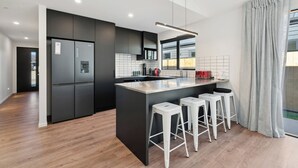 Una cocina moderna con una isla central, taburetes de bar y un refrigerador integrado.