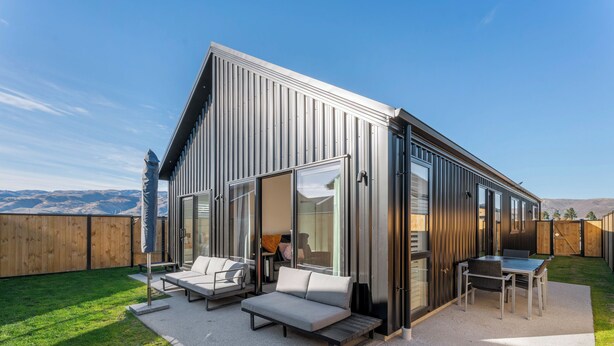 Una casa moderna con un patio que incluye un sofá, una mesa y una silla.