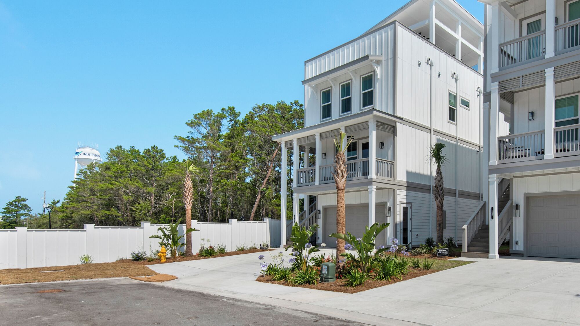 A two-story residential building with a front porch, a garage, and a water tower in the background.