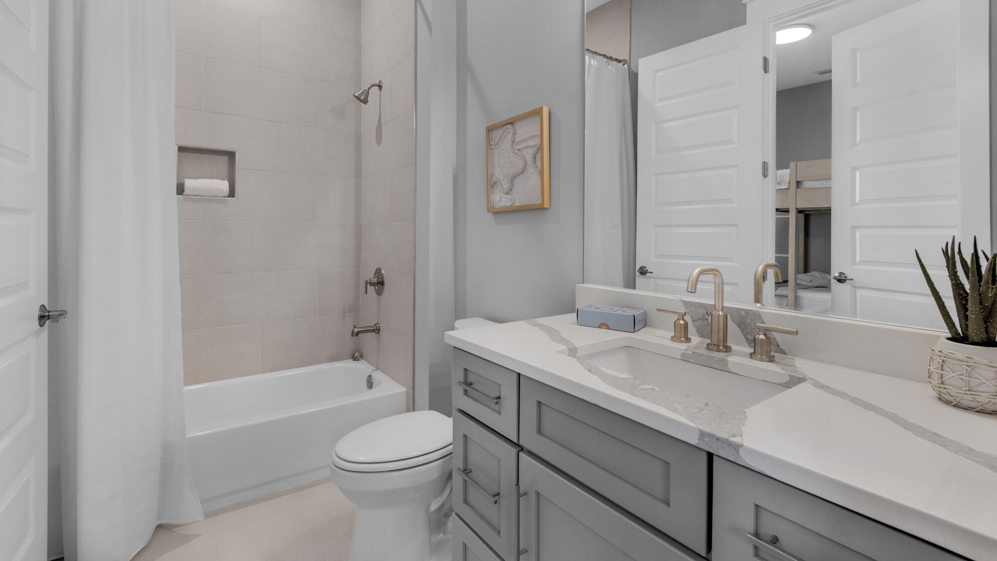 A modern bathroom with a bathtub, toilet, vanity with a sink, and a large mirror.
