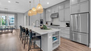 Una cocina moderna con una isla grande, electrodomésticos de acero inoxidable y un comedor con taburetes de bar.