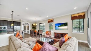 A spacious living area with a sofa set, a dining table, and chairs. There is a kitchen area with cabinets and a countertop. - Main Street USA in Luxury Reunion Home (Reunion)