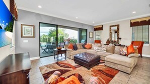 A modern living room with a sofa set, a coffee table, and a TV mounted on the wall. - Main Street USA in Luxury Reunion Home (Reunion)