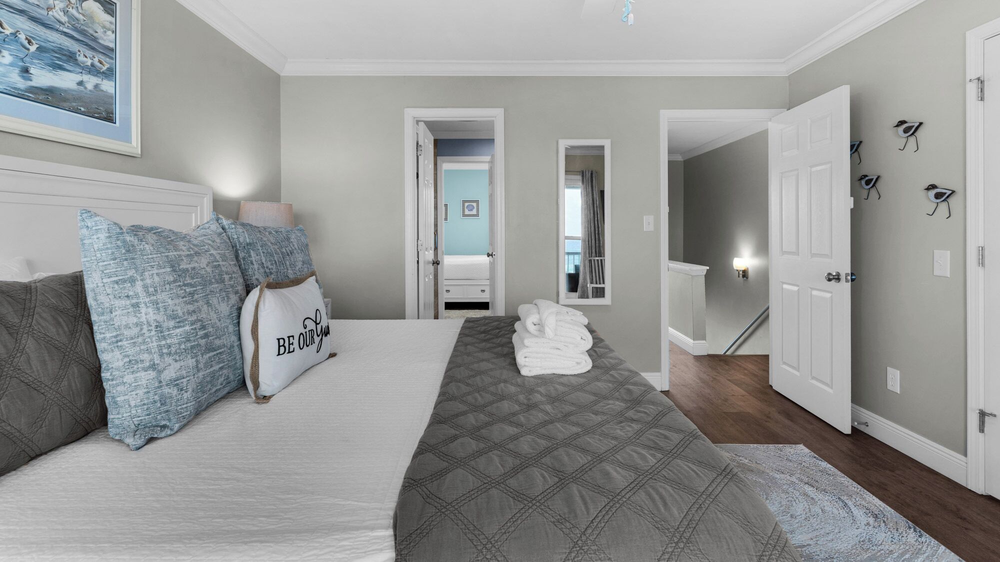 A bedroom with a bed, pillows, a quilt, and a painting on the wall.