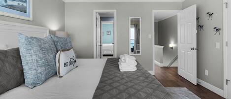 A bedroom with a bed, pillows, a quilt, and a painting on the wall.