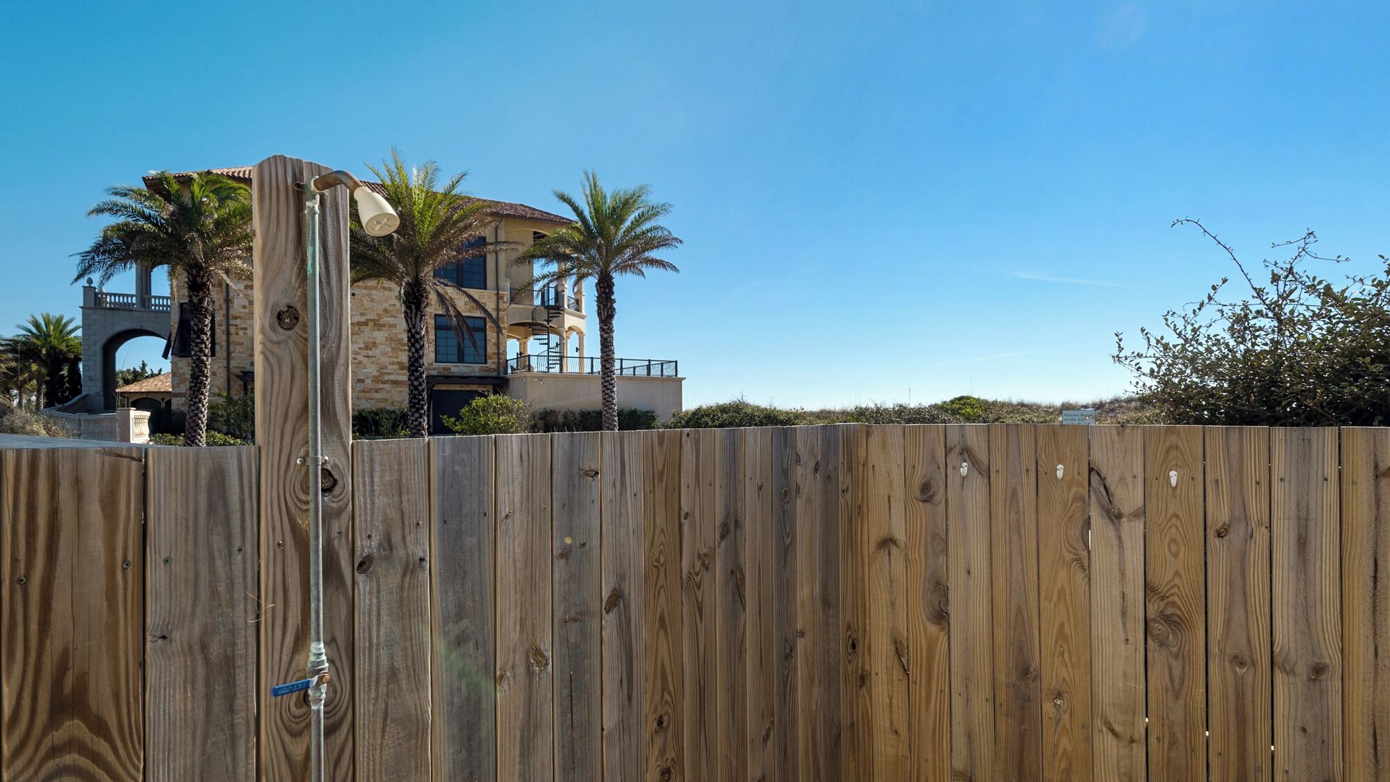A two-story house with a balcony, surrounded by a wooden fence.