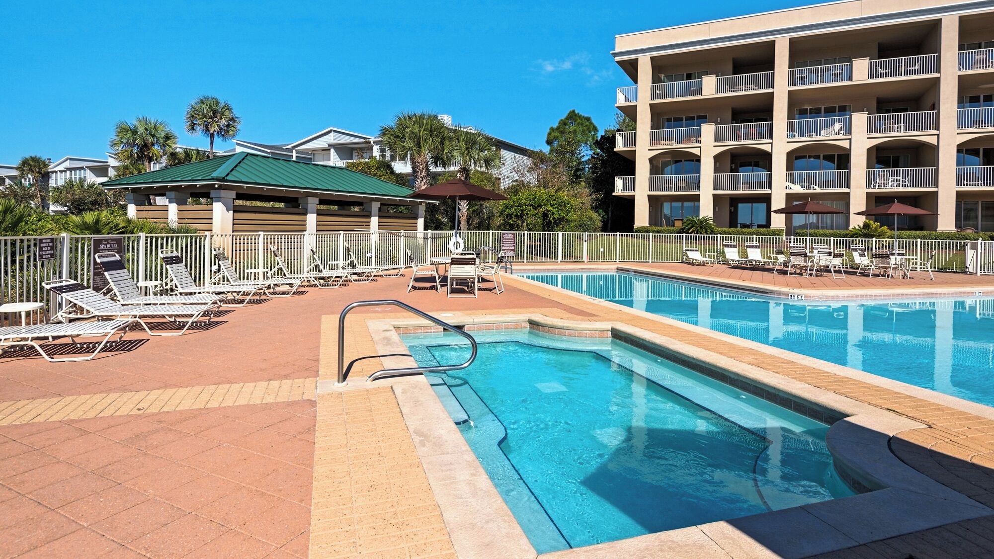A pool area with lounge chairs and a building with balconies.