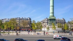 A busy urban street with a prominent green monument, historic buildings, and a clear blue sky. - 397 Suite Glamour - Superb Studio in Paris (Paris 10 Entrepôt)