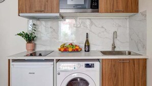 A compact kitchen with wooden cabinets, a microwave, a dishwasher, and a washing machine. - 397 Suite Glamour - Superb Studio in Paris (Paris 10 Entrepôt)