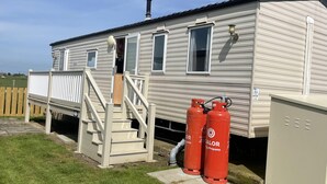 A mobile home with a staircase, propane tanks, and a utility box. - Remarkable 2-bed Holiday Home in Whitstable (Whitstable)