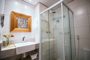 A modern bathroom with a glass-enclosed shower, a wooden-framed mirror, and a white sink.