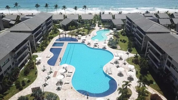 Ein Resort mit großzügiger Poolanlage, mehreren Schwimmbecken und Blick auf den Strand.