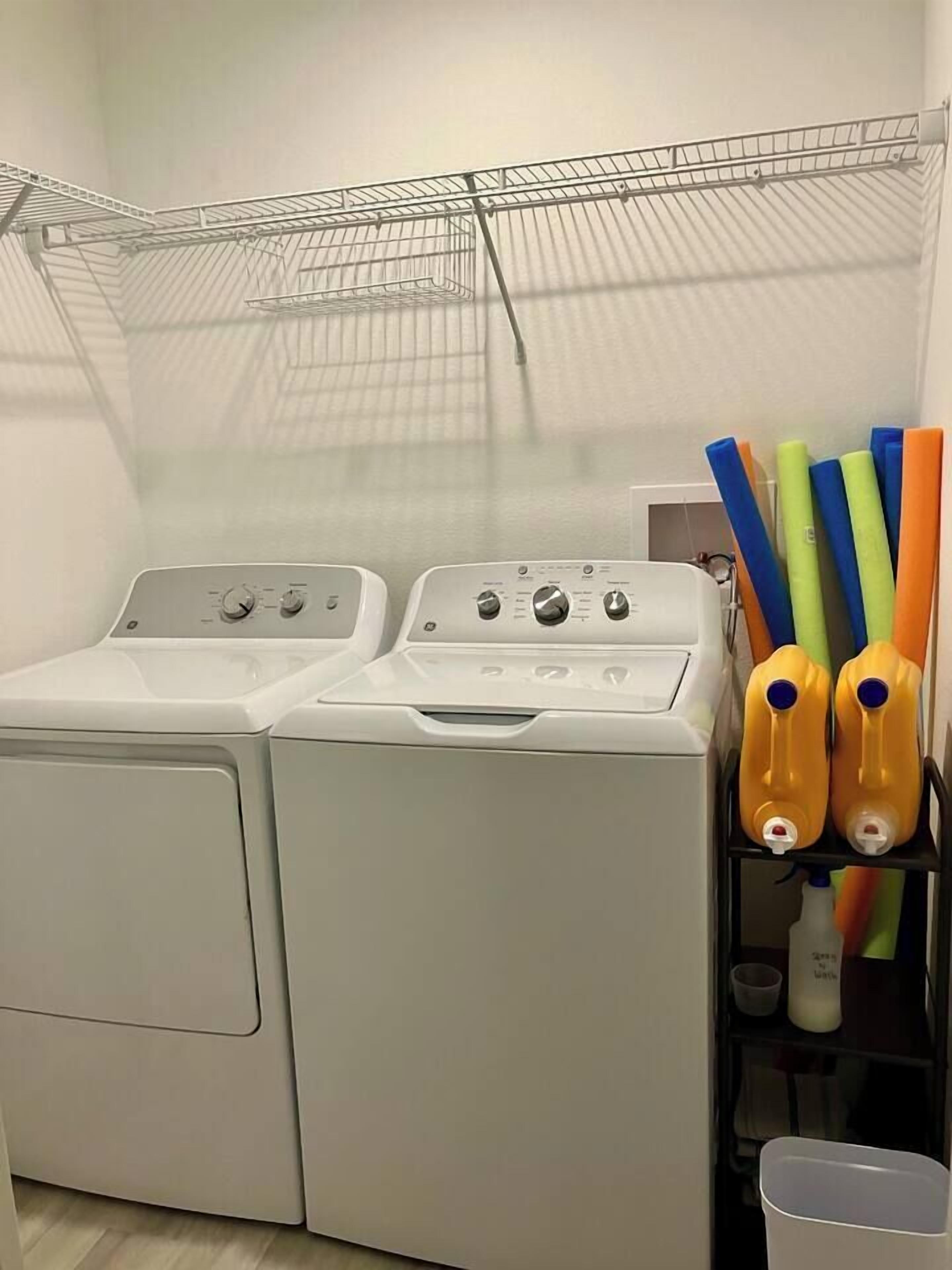 A laundry area with two white front-loading washing machines and a metal drying rack.