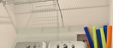 A laundry area with two white front-loading washing machines and a metal drying rack.