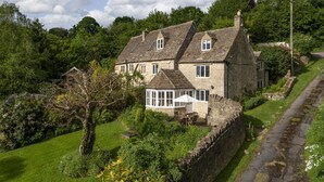 A stone house with a large garden and a paved path.