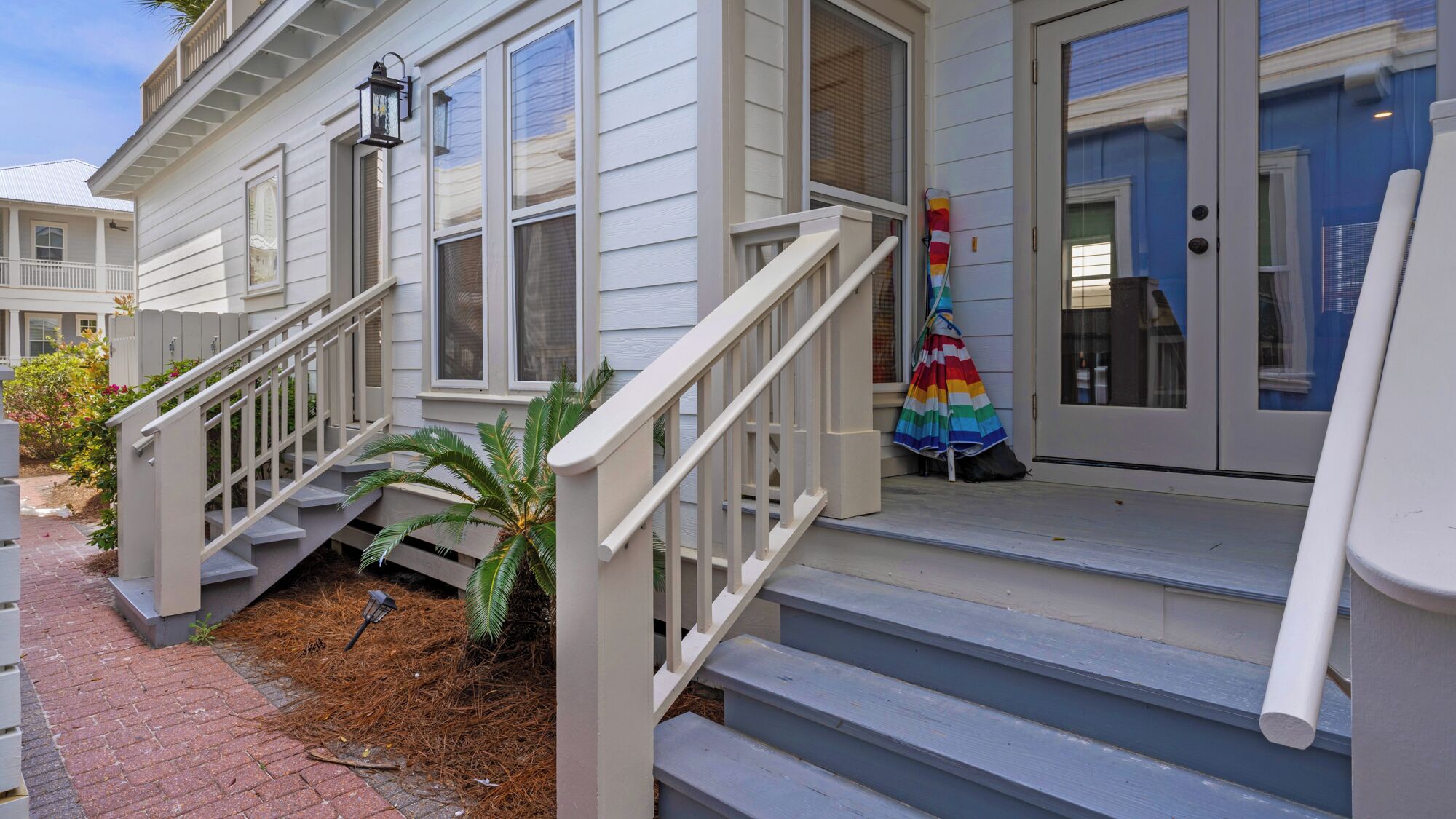 A two-story house with a front porch, a staircase, and a colorful umbrella.