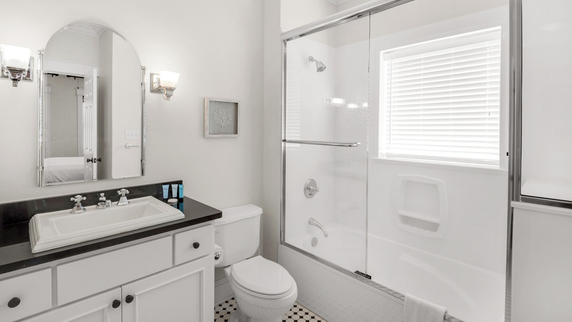 Un baño con lavamanos blanco, espejo, inodoro y ducha con mampara de vidrio.