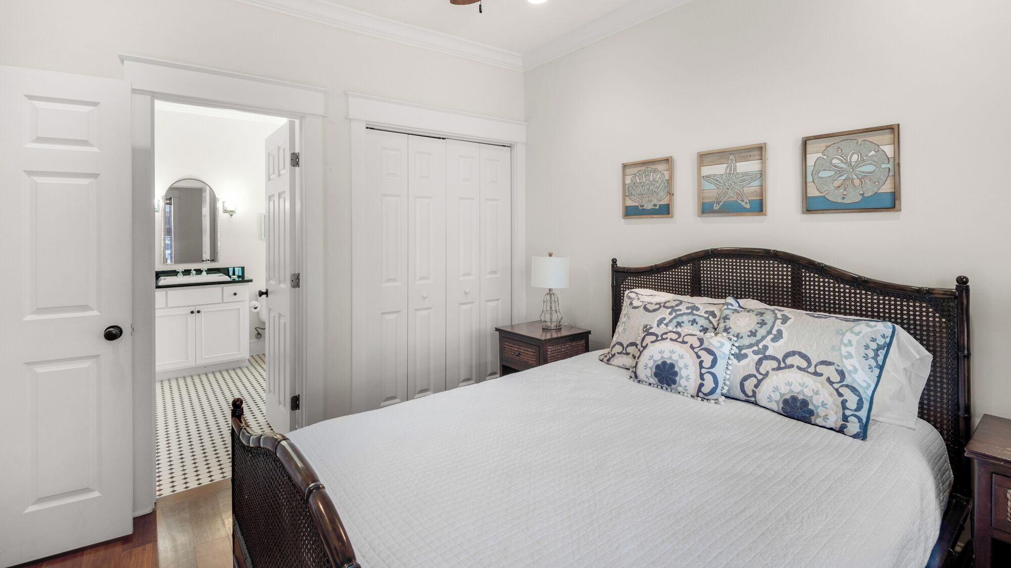 Un dormitorio con una cama grande, una mesita de noche, un aparador y una puerta que da a un baño.