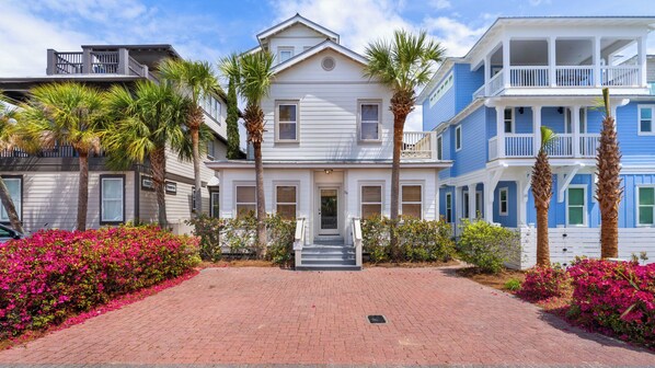A row of coastal-style houses with a brick pathway and tropical plants. - Seacrest Beach Home for 17, Huge Resort Pool & Beach Tram (Panama City Beach)