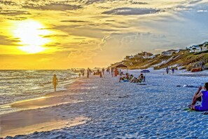Una playa con gente tomando el sol y paseando por la orilla.