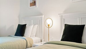 Une chambre d’hôtel avec deux lits simples, une table de chevet avec une lampe et un tableau encadré au mur.