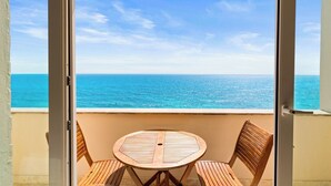 A balcony with a round wooden table and two chairs, overlooking a clear blue sea. - Penthouse w/ Private Rooftop Pool, 360° Views (Isla Mujeres)