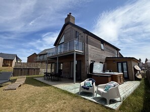 Una casa moderna con patio, mobiliario exterior y jacuzzi.