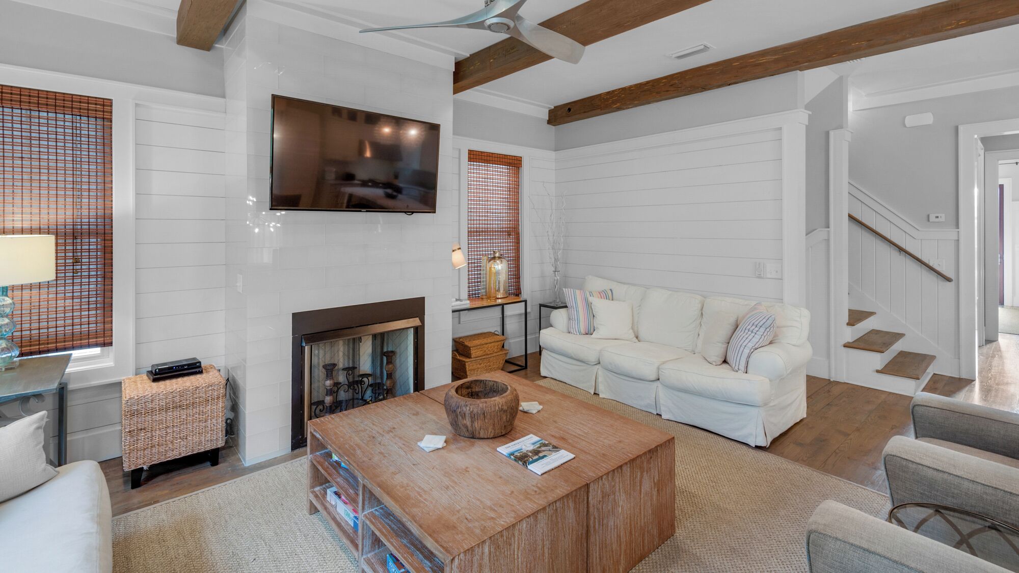 A spacious living room with a fireplace, a sofa, a coffee table, and a television mounted on the wall.
