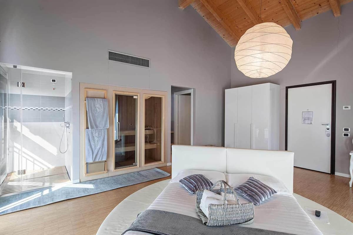 Ein modernes Schlafzimmer mit einem großen Bett, einem begehbaren Kleiderschrank und einer Duschkabine aus Glas.