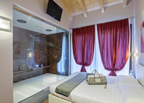 A modern hotel room with a large bed, a glass shower enclosure, and a television mounted on the ceiling. - TENUTA VALDORSO AGRI RESORT (Montechiaro d'Acqui)